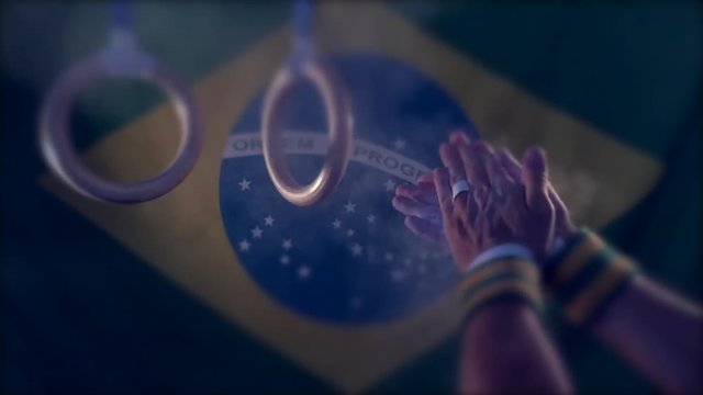 Taped hands of gymnast clapping white chalk powder into a cloud under gymnastic rings in front of a Brazil flag background