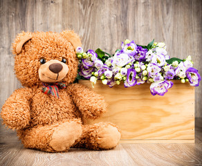 Obraz premium Flowers and a teddy bear on wooden background