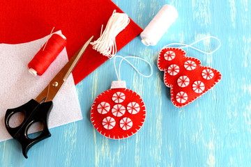 Christmas felt red ball and tree, scissors, white and red threads, needle, cord on blue wooden...