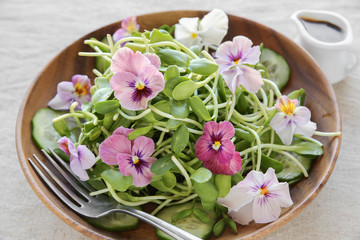 Obraz na płótnie Canvas Sunflower sprouts, cucumber and edible flowers salad on wooden b