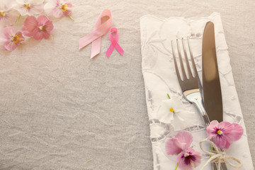 Pink ribbon day table setting with pink flowers, copy space toning background