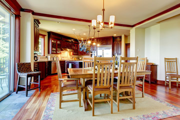 View of honey color dining table set with kitchen in the background.