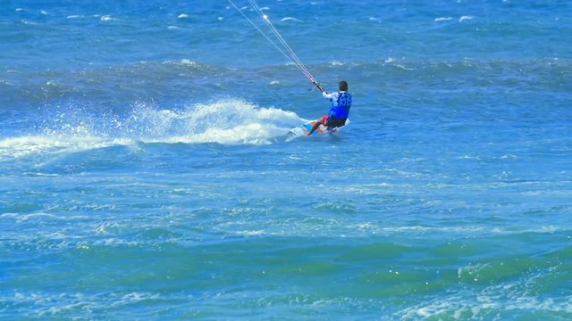 Sportive man surfing on kite board in ocean