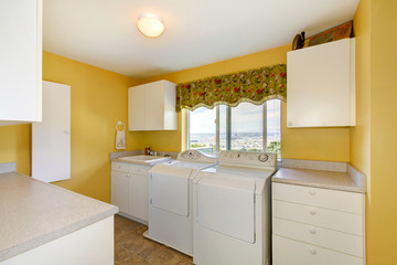 Old laundry room with white cabinets and yellow walls.