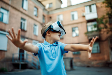 Fascinated little boy using VR virtual reality goggles. outdoor