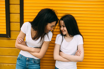 mother and her cute daughter, against wall