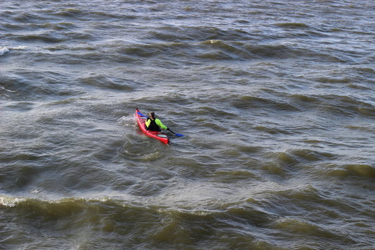 Kayaking on the stormy lake. Man in red kayak