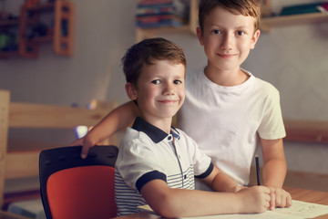 Little schoolboy with brother helps write homework