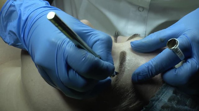 Microblading procedure. Master works with the eyebrows. Semi-permanent make-up.