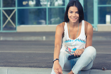 young pretty woman sitting with smartphone listening to the musi