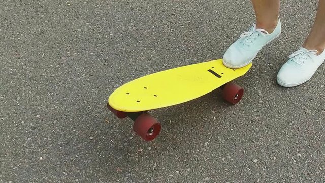 teenage girl toot putting short skateboard on end