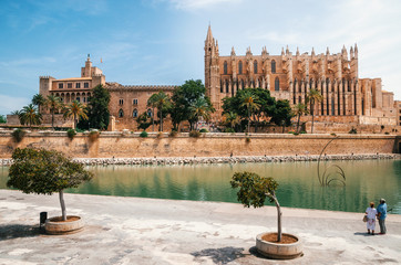 Couple of tourists looking at La Seu, the gothic medieval Cathedral of Palma de Mallorca and La Almudaina Royal Palace, Spain. The Cathedral of Santa Maria © bortnikau