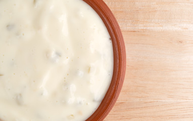 Small bowl of tartar sauce on a wood table top close view.