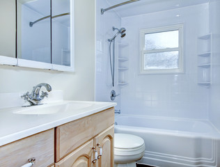 Bathroom interior with light tone vanity cabinet and tile floor.