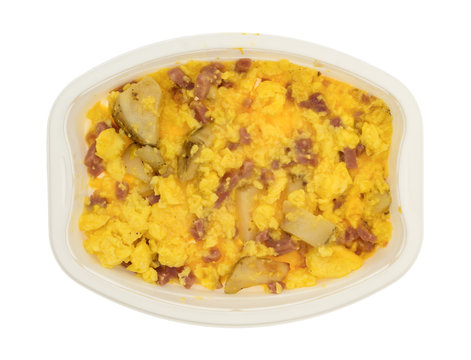 Ham eggs and potatoes breakfast TV dinner in a tray top view on a white background.