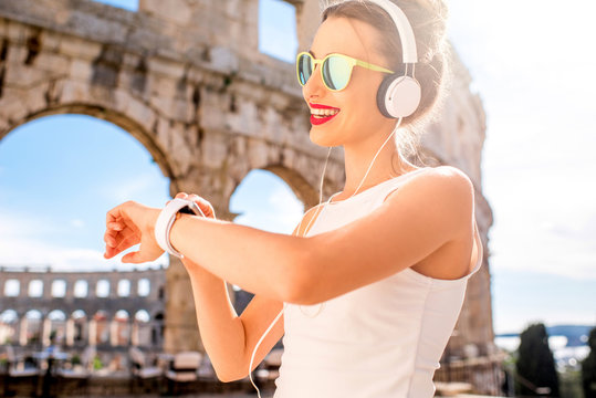Young sports woman looking at smartwatch during the training near the ancient amphitheatre in Pula city.