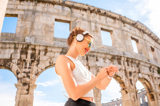 Young sports woman looking at smartwatch during the training near the ancient amphitheatre in Pula city.