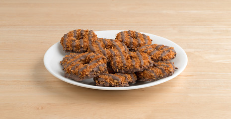 Fudge coconut caramel cookies on a white plate atop a wood table.