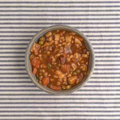 Bowl of beef stew on a tablecloth top view.