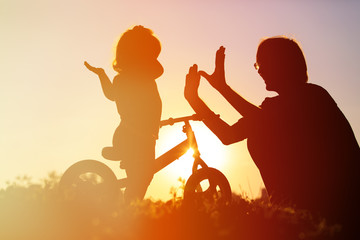 father and daughter riding bike at sunset