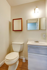 Simple bathroom with small washbasin cabinet and mirror.
