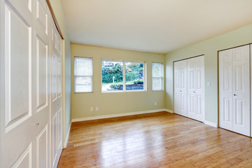Obraz premium Empty room interior with hardwood floor and three closets.