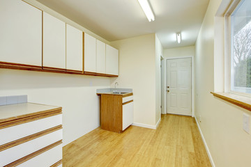Bright laundry room interior with cabinets and hardwood flooring.