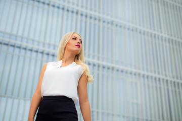 Young attractive blonde business woman over modern background