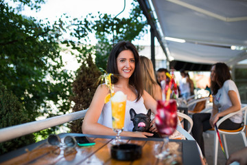 Beautiful brunette girl in a cafeteria keeping adorable French bulldog puppy in her lap.