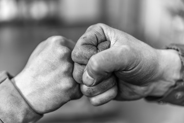 Two fellow workers greeting each other with a handshake using their fists as a symbol of companionship, friendship and solidarity. - obrazy, fototapety, plakaty