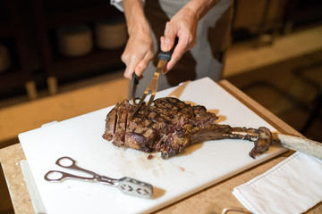 Chef with knife and fork. Professional chef in a restaurant or hotel prepares or cut up t-bone...