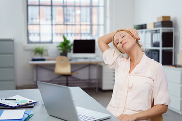 frau im büro dehnt ihren nacken