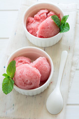 Watermelon sorbet ice cream in bowl on white wooden background