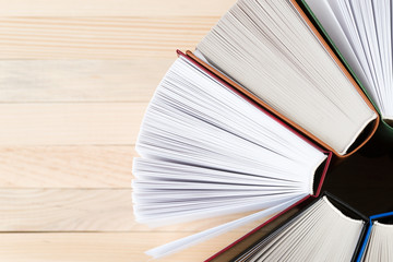 Open book, stack of hardback books on wooden table. Back to school. Copy space