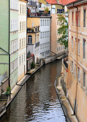 Narrow water canal with old colorful buildings in perspective. Vertical view. Prague, Czech Republic.