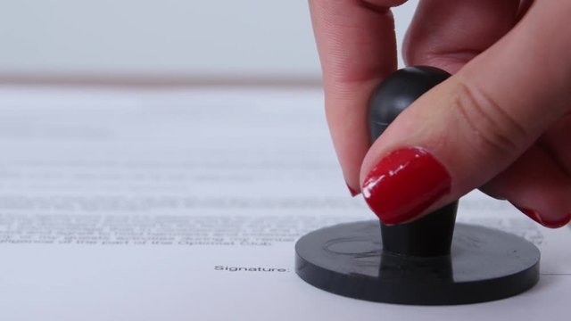 Woman puts a company stamp on the document. Dynamic change of focus. Close up