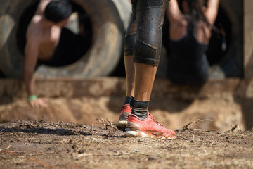 Mud race runners,detail of the legs,in the background obstruction tires