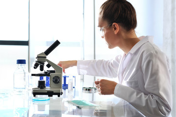 Chemik bada próbkę pod mikroskopem.. Chemik pracuje w laboratorium  - obrazy, fototapety, plakaty