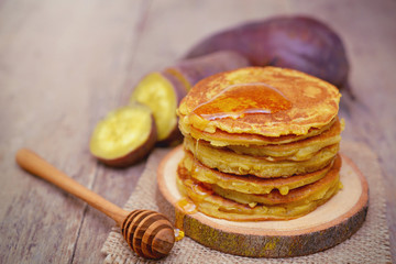 Sweet potato pancakes with honey on wooden plate.