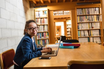 Young woman using laptop in library