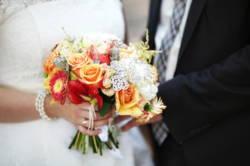 Bride and groom holding colourful wedding bouquet. Marriage concept