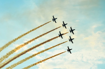 Acrobatic planes doing acrobatics at an Airshow flying at sunset