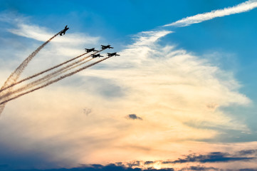 Acrobatic planes in action at an Airshow flying at sunset / dusk