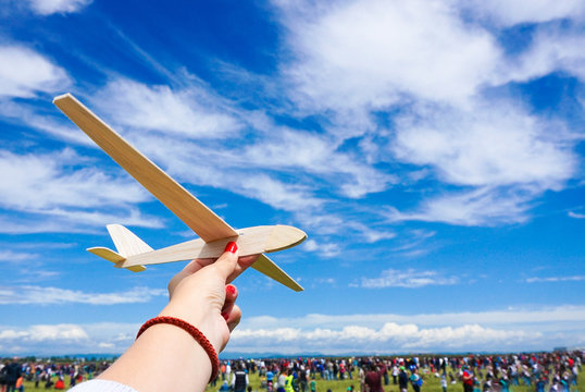 Girl Holding Toy Plane At An Airshow With Crowd In The Backgroun