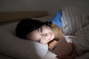 Fototapeta na wymiar Woman use of mobile phone and lying on bed