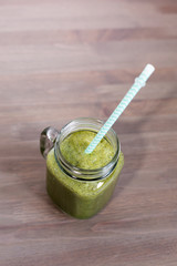 A green smoothie in a mason jar on wooden background