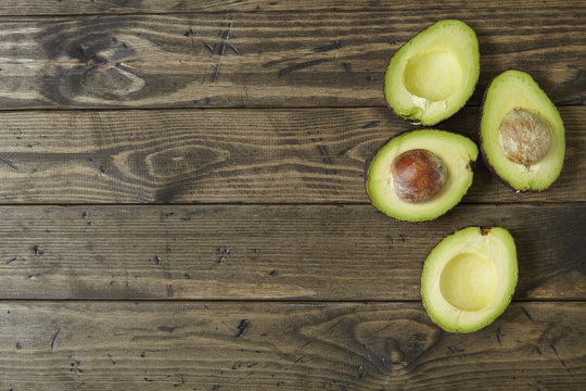 Halved avocados on a rustic wooden kitchen counter background forming a page border