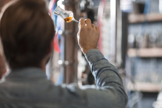 Man in distillery examining glass with liquor