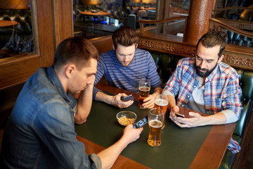 men with smartphones drinking beer at bar or pub