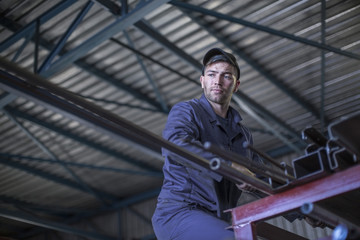 Mechanic in workshop taking steel bar from high rack